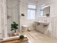 Großzügiges und helles Badezimmer mit Badewanne, Dusche, Handtücher, Toilettenpapier, Seife, Duschgel Großzügiges und helles Badezimmer mit Badewanne, Dusche, Handtücher, Toilettenpapier, Seife, Duschgel
