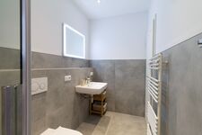 Helles modernes Badezimmer mit Handtüchern und Spiegelbeleuchtung Helles modernes Badezimmer mit Handtüchern und Spiegelbeleuchtung