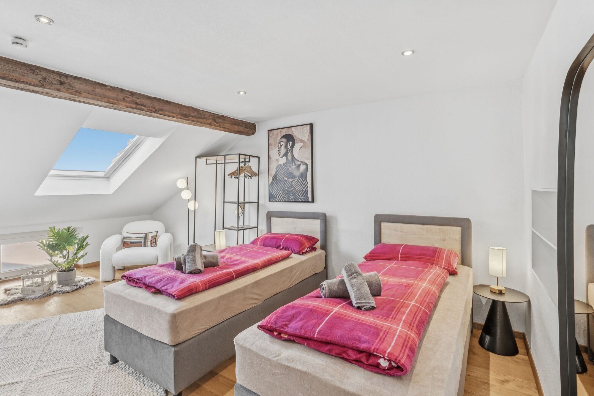 Zwei Einzelbetten mit pinkfarbener Bettwäsche unter einer Dachschräge, Dachfenster lässt Tageslicht Zwei Einzelbetten mit pinkfarbener Bettwäsche unter einer Dachschräge, Dachfenster lässt Tageslicht