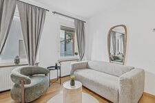 Helles Wohnzimmer mit grauem Sofa, rundem Beistelltisch und großem Spiegel an der Wand. Helles Wohnzimmer mit grauem Sofa, rundem Beistelltisch und großem Spiegel an der Wand.