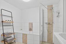 Weißes Badezimmer mit Duschkabine, Badewanne, Handtücher hängen an der Wand. Weißes Badezimmer mit Duschkabine, Badewanne, Handtücher hängen an der Wand.