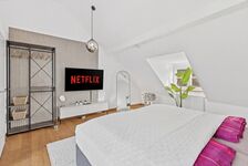 Großes Doppelbett, Smart-TV auf Lamellenverkleidung, offenes Metallregal als Kleidersystem, runde Pe Großes Doppelbett, Smart-TV auf Lamellenverkleidung, offenes Metallregal als Kleidersystem, runde Pe