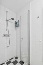 Bodenebene Dusche mit Regenduschkopf, weiße Fliesen, Duschgel-Flaschen an der Wand. Bodenebene Dusche mit Regenduschkopf, weiße Fliesen, Duschgel-Flaschen an der Wand.