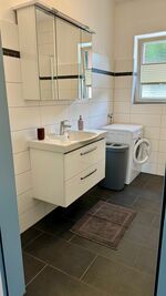 Großes Badezimmer mit Dusche, Waschbecken und Waschmaschine Großes Badezimmer mit Dusche, Waschbecken und Waschmaschine