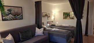 trennbares Wohn- und Schlafzimmer mit zwei Hotel-Boxspringbetten (zusammenschiebbar) sowie einer großen 160x200cm großen Schlafcouch. Davor der 55` große SmartTV