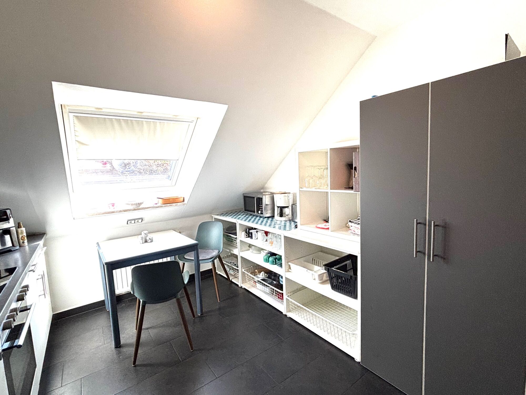 Küchenregale mit Mikrowelle und Kaffeemaschine sowie Putzschrank