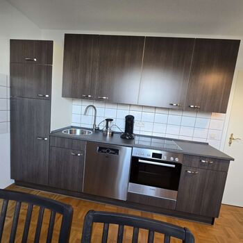 Voll ausgestattete Küche mit Backofen, Kochfeld, Geschirrspüler, Kühlschrank und Kaffeemaschine.