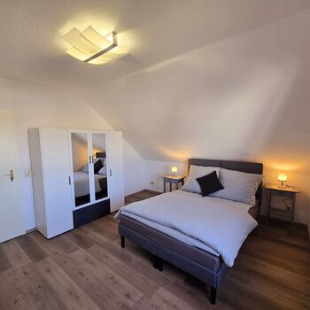 Geräumiges Schlafzimmer der Dachgeschosswohnung mit Doppelbett, Kleiderschrank und viel Platz.