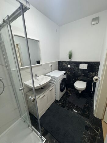 Badezimmer mit Dusche und Waschmaschine 