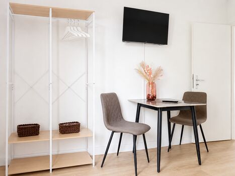 Schlafzimmer2 im 1.OG: Der Schlafraum verfügt über ein großes Kleiderregal, einen Smart-TV mit verstellbarer Wandhalterung sowie einen Ess- oder Arbeitsbereich. Für zusätzlichen Komfort und Privatsphäre ist jede Zimmertür abschließbar.