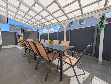 Überdachte Terrasse mit großem Esstisch und Gartenstühle für 10P