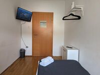 Einzelzimmer mit TV und Kleiderablage
