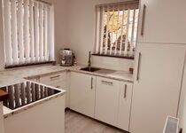 Neuwertige, voll ausgestattete Küche mit Backofen, Kühlschrank mit Tiefkühlfach, Dampfgarer, Toaster und umfangreichen Koch- und Küchenutensilien.