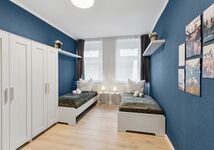 Schlafzimmer 1 mit zwei Einzelbetten, Schränken und Arbeitsplatz