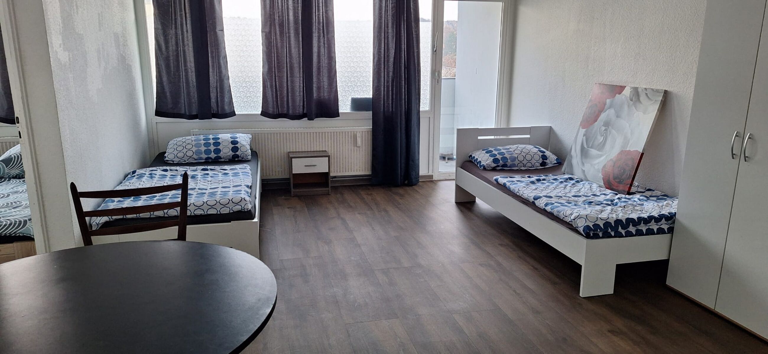 Helles Schlafzimmer mit zwei Einzelbetten, Laminatboden und Tageslicht – ideal für Monteure und Geschäftsreisende.