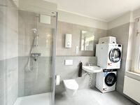Badezimmer mit Dusche, Waschmaschine und Trockner