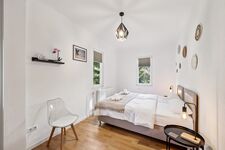 Schlafzimmer 1 mit hochwertigen Boxspringbetten, Nachttischen und einem offenen Kleiderschrank sowie Blick ins Grüne. Die Betten können wahlweise einzeln oder als komfortables Doppelbett gestellt werden.