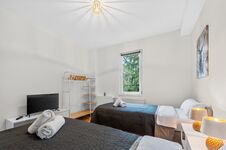 Wohnung 1: Schlafzimmer 2 mit hochwertigen Boxspringbetten, Nachttischen, offenem Kleiderschrank und Smart-TV. Die Betten können flexibel als Einzelbetten oder als komfortables Doppelbett gestellt werden.
