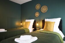 Schlafzimmer 3 - Twin-Schlafzimmer mit zwei Einzelbetten, hochwertiger Bettwäsche, TV, Nachttischlampen und ruhigen Grüntönen.