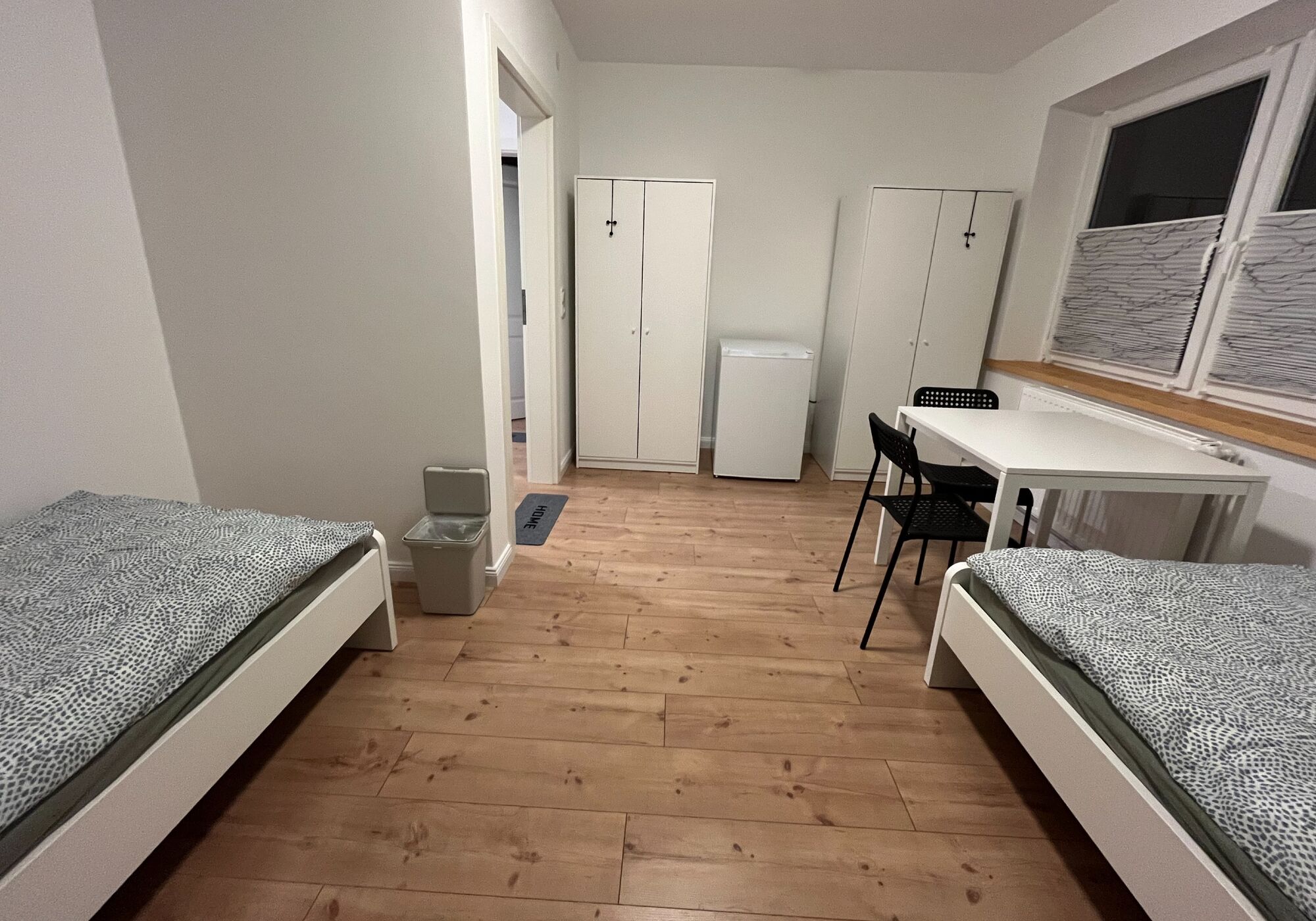 Bettwäsche, Schränke, Esstisch und Kühlschrank im Zimmer