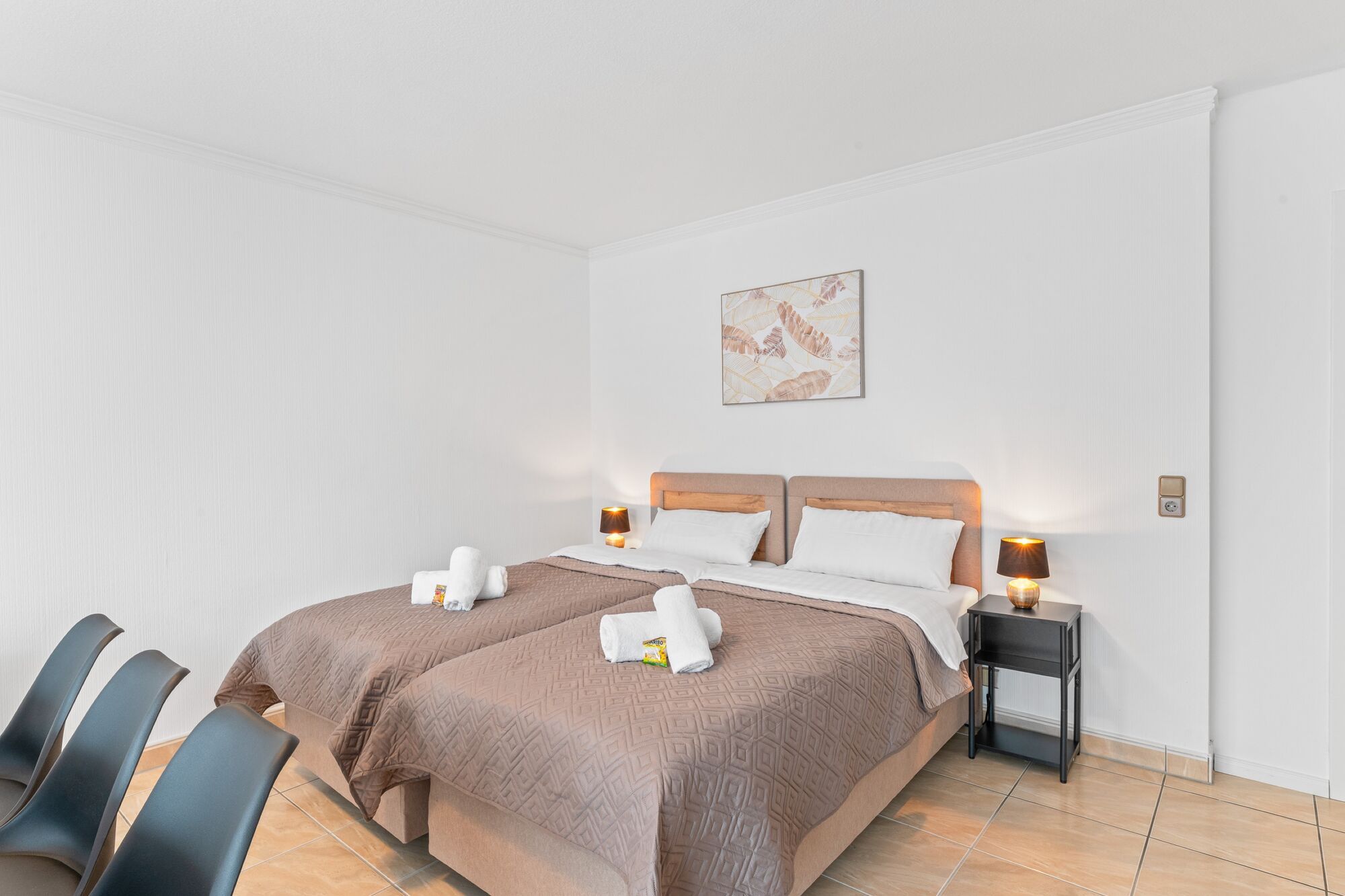 Wohnzimmer mit zwei hochwertigen Boxspringbetten und einem gemütlichen Essbereich. Die Betten können wahlweise einzeln oder als komfortables Doppelbett gestellt werden.