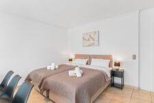 Wohnzimmer mit zwei hochwertigen Boxspringbetten und einem gemütlichen Essbereich. Die Betten können wahlweise einzeln oder als komfortables Doppelbett gestellt werden.