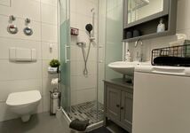 Badezimmer mit Dusche, WC, Waschbecken, Spiegelschrank, Waschbeckenunterschrank und Waschmaschine