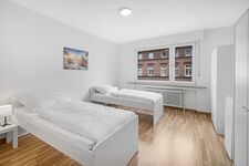 Schlafzimmer 2 mit drei Einzelbetten, Sitzecke und Smart TV