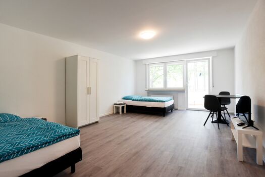Schlafzimmer mit Hotelbetten 100x200, Nachttisch, Schrank, Tisch mit Stühlen, teilweise mit Balkon