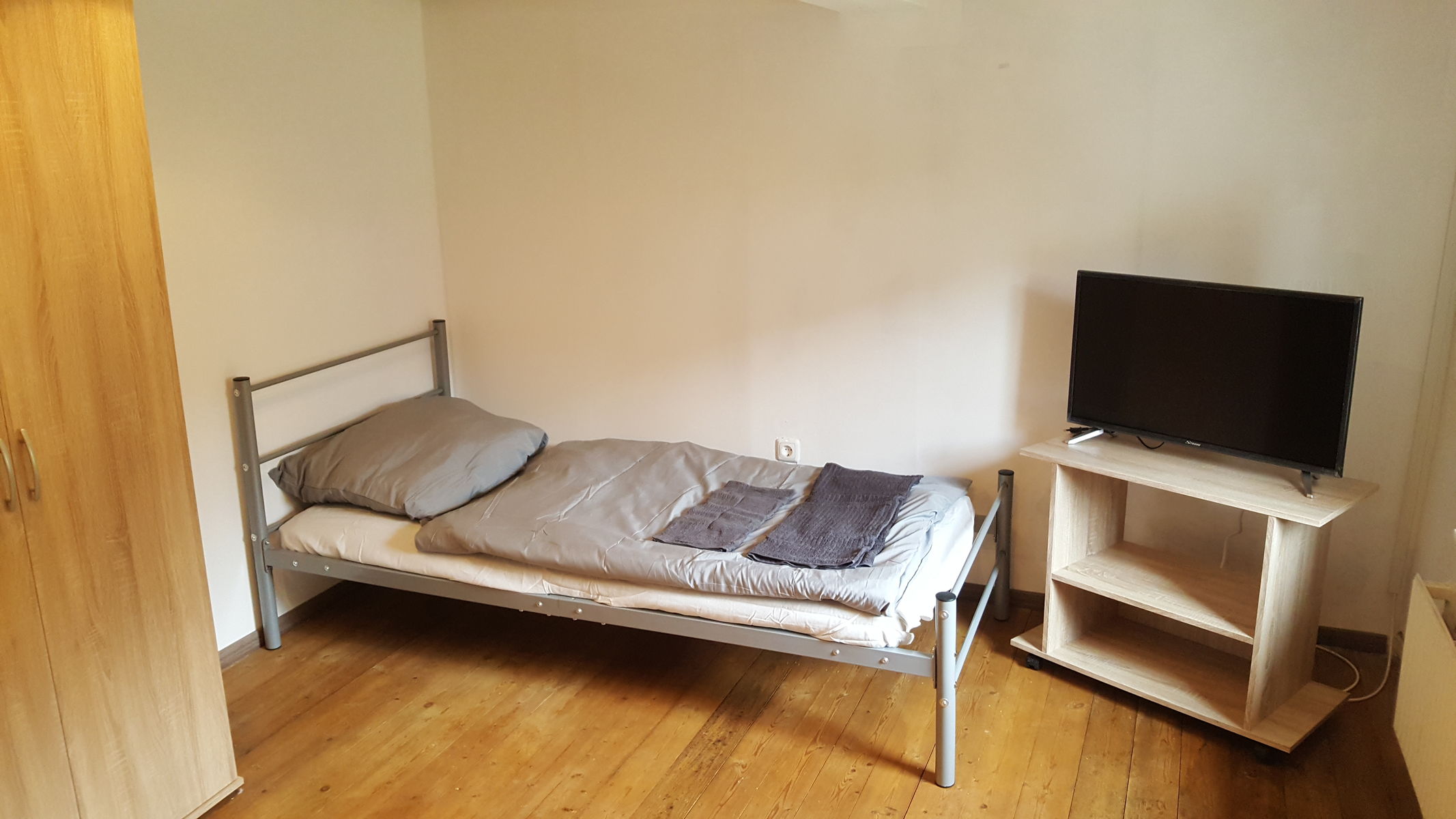 Einzelzimmer mit Bett, Schrank und Tisch