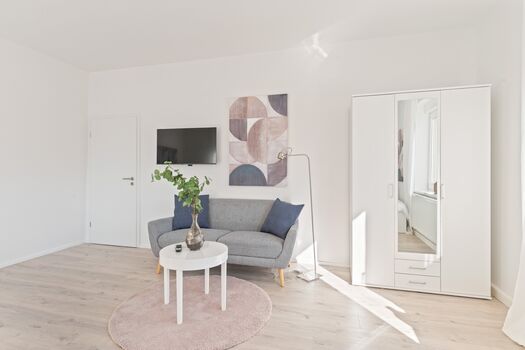 4-Zimmer-Wohnung: Zimmer - 1 Helles Zweibettzimmer mit zwei Einzelbetten. Ausgestattet mit 40 Zoll Smart-TV, Sofa und Sitzbereich mit Tisch. Viel Tageslicht.