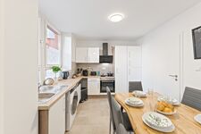 4-Zimmer-Wohnung: Voll ausgestattete Küche Große Küche mit Herd, Backofen, Mikrowelle, zwei Kühlschränken, Spülmaschine und Waschmaschine. Geschirr, Besteck, Töpfe und Pfannen vorhanden. Essbereich mit Tisch und Sitzplätzen.