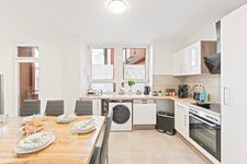 4-Zimmer-Wohnung: Voll ausgestattete Küche Große Küche mit Herd, Backofen, Mikrowelle, zwei Kühlschränken, Spülmaschine und Waschmaschine. Geschirr, Besteck, Töpfe und Pfannen vorhanden. Essbereich mit Tisch und Sitzplätzen.