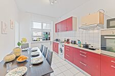 3-Zimmer-Wohnung: Küche Voll ausgestattete Küche mit Herd, Backofen, Mikrowelle, zwei Kühlschränken und Waschmaschine. Geschirr, Besteck, Töpfe und Pfannen vorhanden. Essbereich mit Tisch und Sitzplätzen.