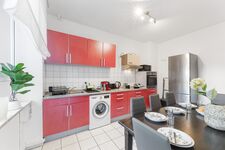 3-Zimmer-Wohnung: Küche Voll ausgestattete Küche mit Herd, Backofen, Mikrowelle, zwei Kühlschränken und Waschmaschine. Geschirr, Besteck, Töpfe und Pfannen vorhanden. Essbereich mit Tisch und Sitzplätzen.