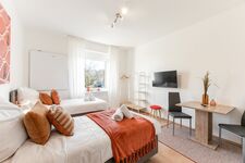 3-Zimmer-Wohnung: Zimmer 1 – Helles Zimmer mit zwei Einzelbetten. Ausgestattet mit 40 Zoll Smart-TV, Schreibtisch, Stuhl und Stauraum. Große Fenster sorgen für viel Tageslicht.