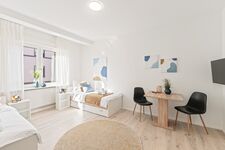 4-Zimmer-Wohnung: Zimmer 3 - Helles Zweibettzimmer mit zwei Einzelbetten. Ausgestattet mit Nachttischen, Sessel, Stauraum und 40 Zoll Smart-TV. Große Fenster sorgen für viel Tageslicht.