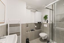 4-Zimmer-Wohnung: Neues Badezimmer Modern ausgestattetes Badezimmer mit Dusche, WC und Waschbecken. Helle Fliesen und funktionale Ausstattung.